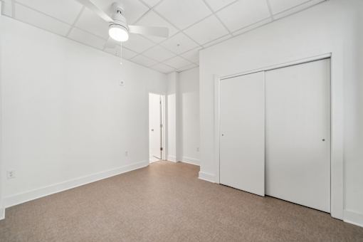 A white room with a ceiling fan and carpeted floor.