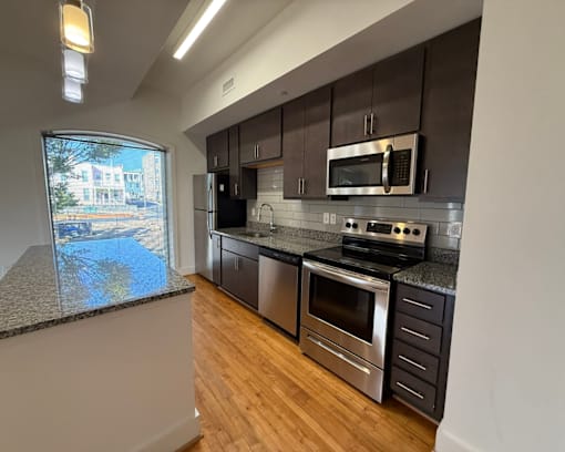A modern kitchen with stainless steel appliances and wooden floors.