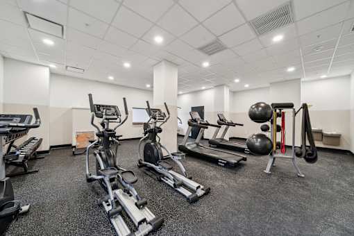 A spacious gym with a variety of equipment including treadmills, stationary bikes, and weight machines.