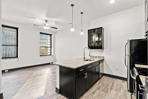 A kitchen with black cabinets and a marble countertop.
