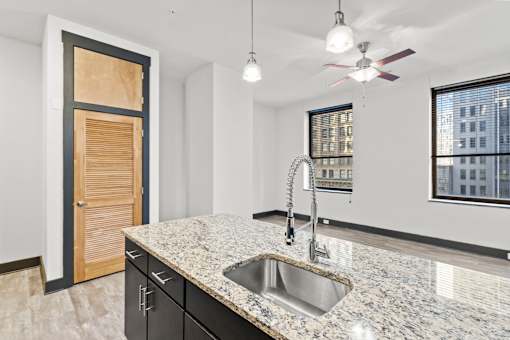 A kitchen with a granite countertop and a window overlooking a cityscape.