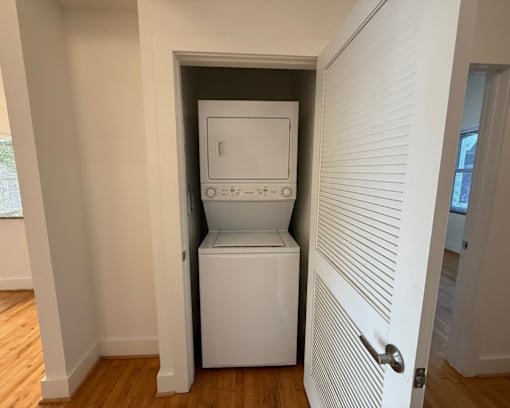 A white washing machine is in a small alcove in a room.