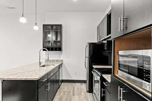 A modern kitchen with black cabinets and stainless steel appliances.