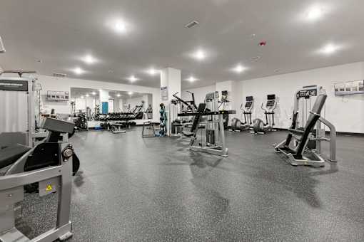 A black and white image of a gym with various exercise equipment.