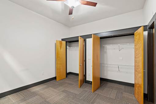 A room with a carpeted floor and a ceiling fan.