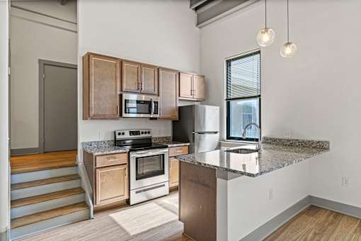 A kitchen with a granite countertop and stainless steel appliances.