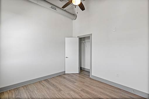 A room with a white door and a ceiling fan.