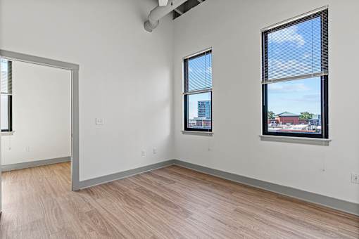 A room with a white wall and a window with blinds.