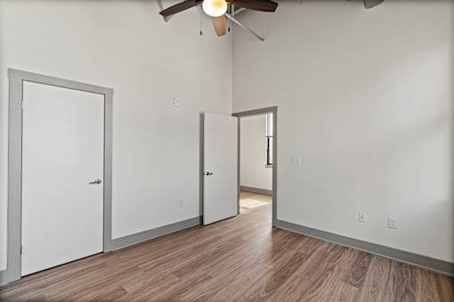 A room with a ceiling fan and three doors.