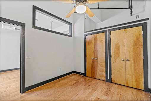 A room with a ceiling fan and wooden floors.