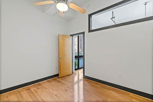 A room with a ceiling fan and a door leading to another room.