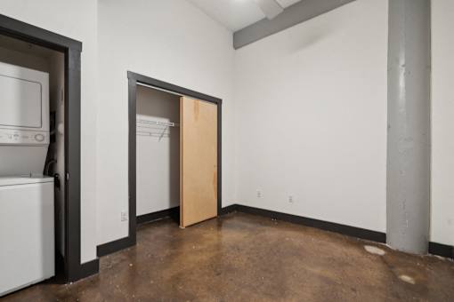 A room with a brown floor and a white wall with a door open.