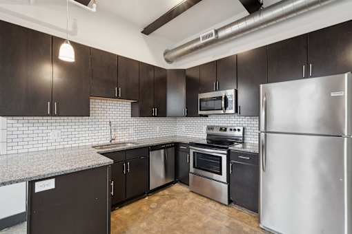 A kitchen with black cabinets and stainless steel appliances.