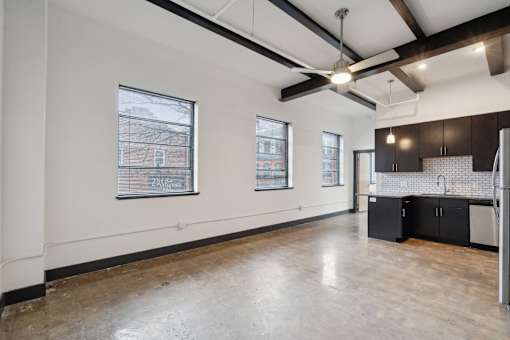 A large empty room with a kitchen area on the right side.