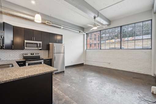 A kitchen with black cabinets and a granite countertop.