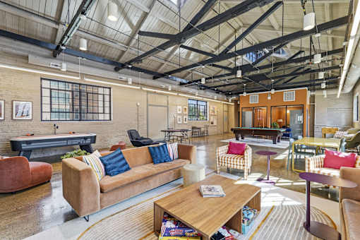 A large, open-plan living area with a variety of seating options and a high ceiling with exposed beams.
