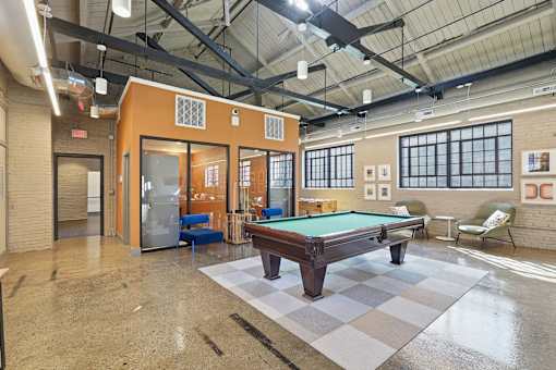 A billiard table is in the middle of a room with a pool table chair and a pool table table.