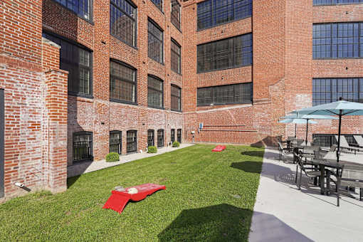 A red blanket is on the grass in front of a brick building.