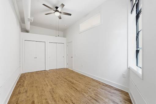 A room with a ceiling fan and wooden flooring.