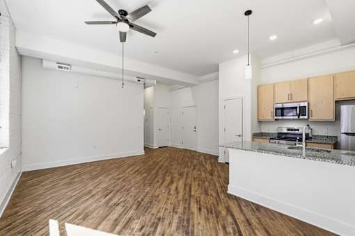 A kitchen with a fan on the ceiling and wooden floors.