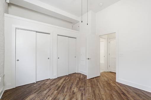 A room with white walls and wooden floors with four white doors.