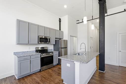 A modern kitchen with a granite countertop and stainless steel appliances.