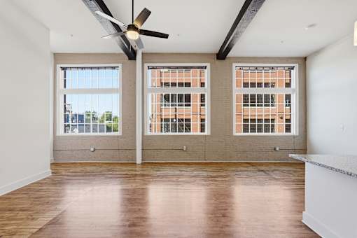 A room with a ceiling fan and three windows.