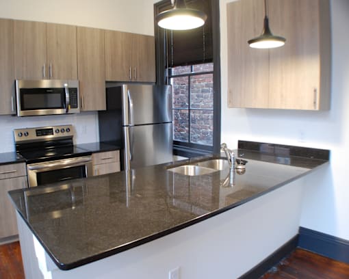 A kitchen with a granite counter top and stainless steel appliances.