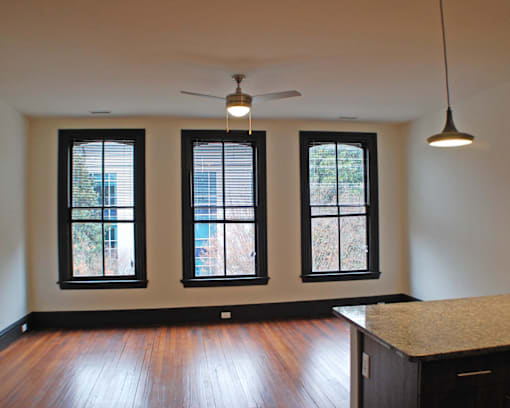 A room with a ceiling fan and three windows.