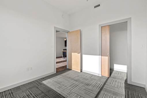 A room with a carpeted floor and two open doors.