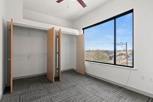 A room with a ceiling fan and a window overlooking a landscape.