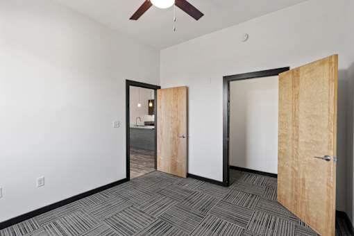 A room with a ceiling fan and three doors.
