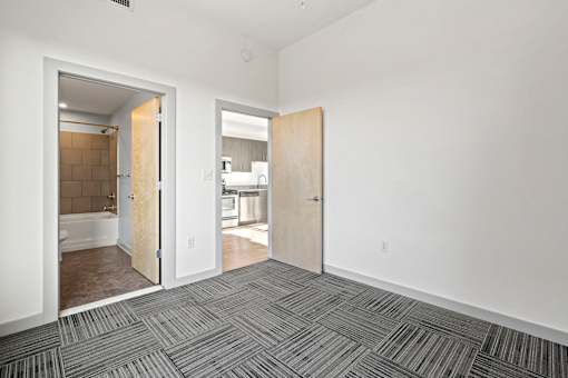 A room with a carpeted floor and two open doors.