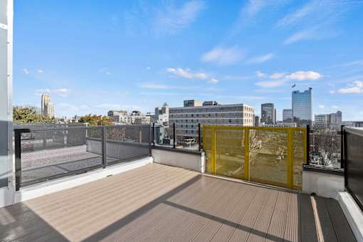 A rooftop with a yellow gate and a view of the city.