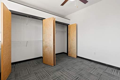 A room with a carpeted floor and a ceiling fan.