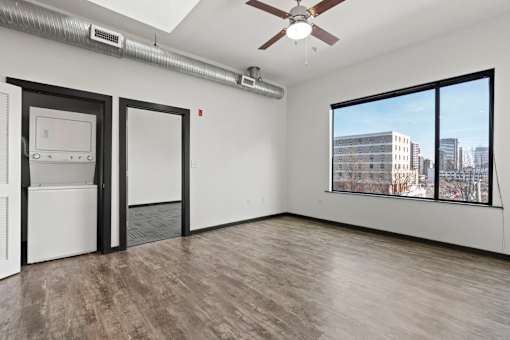A room with a ceiling fan and a window overlooking a cityscape.