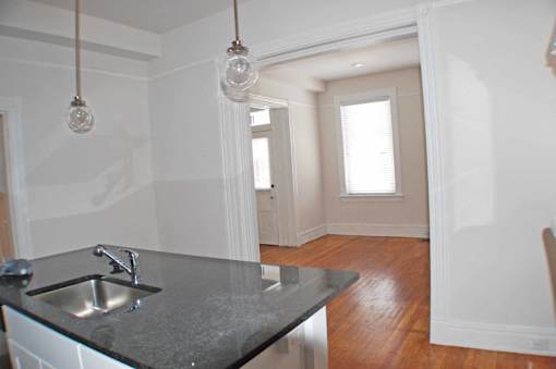 A kitchen with a black counter top and a sink.