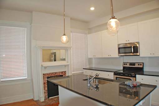 A kitchen with a black counter top and white cabinets.