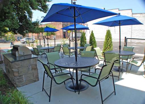 A patio with a table and chairs under blue umbrellas.