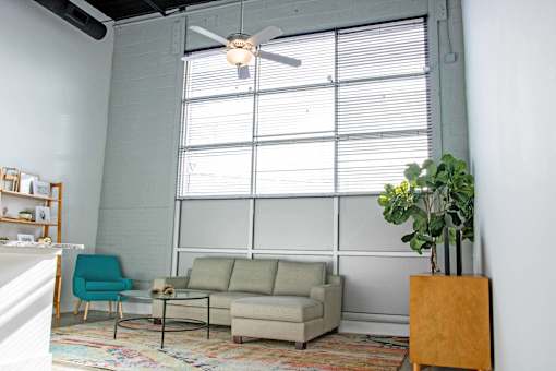 A living room with a couch, chair, and a potted plant.