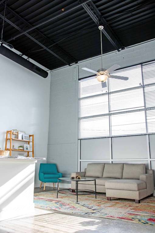 A living room with a blue chair, a beige couch, and a rug.
