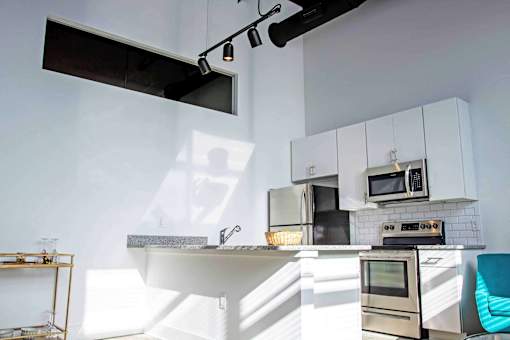 A modern kitchen with a white countertop and stainless steel appliances.