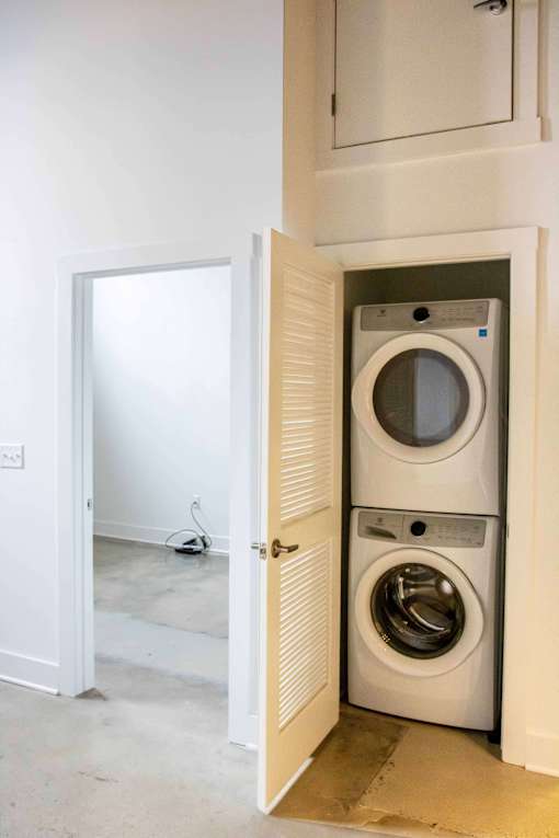 A white door is open to a small laundry room with a washer and dryer.