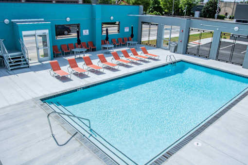 A swimming pool with red chairs around it.