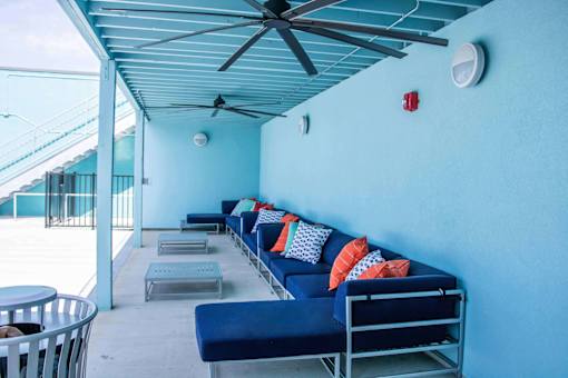 A blue couch with pillows and a fan on the ceiling.