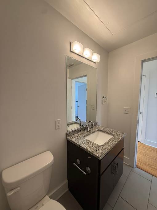 A bathroom with a sink, toilet and mirror.
