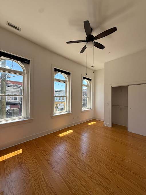 A room with a ceiling fan and wooden floors.