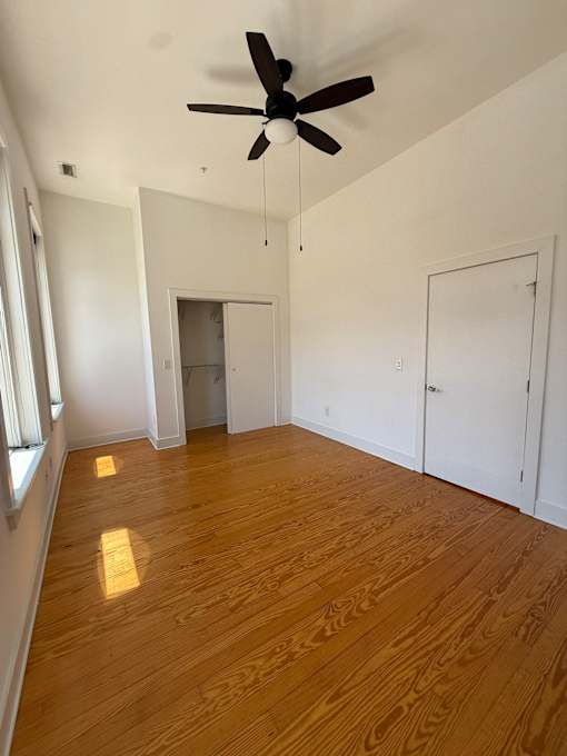 A room with a ceiling fan and wooden flooring.