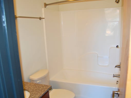 A white toilet sits next to a white bathtub in a bathroom.