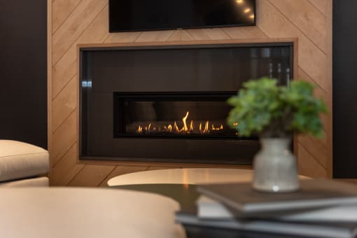 a fireplace with wood paneling and a vase of flowers on a coffee table at The Bend Arbordale, Virginia, 23188